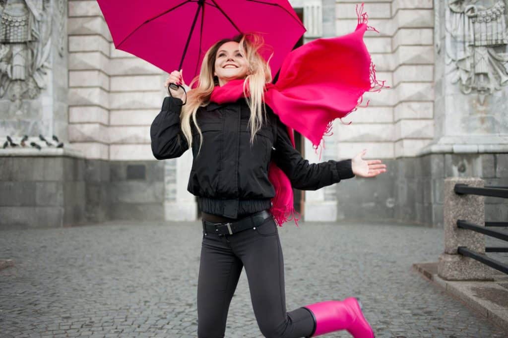 Sexy blonde Frau trägt modische Gummistiefel und posiert im Freien.