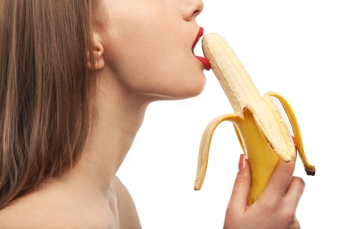 Frau mit roten Lippen übt Deepthroat-Technik mit einer Banane