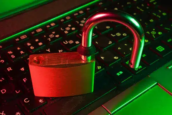 Geöffnetes Vorhängeschloss auf einer beleuchteten Laptop-Tastatur.